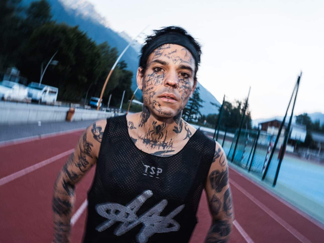 Tattooed athlete running on track.