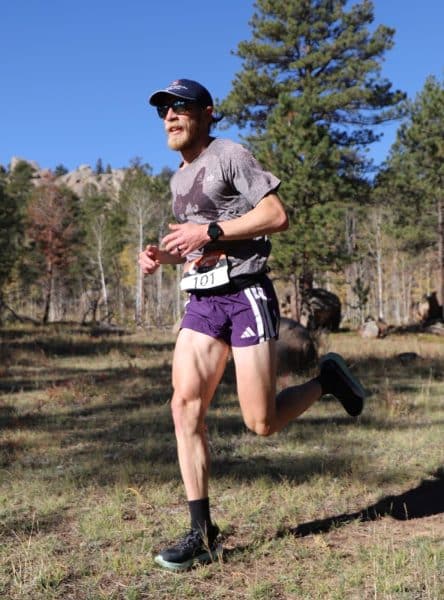 Runner Clint Anders in a forested landscape.