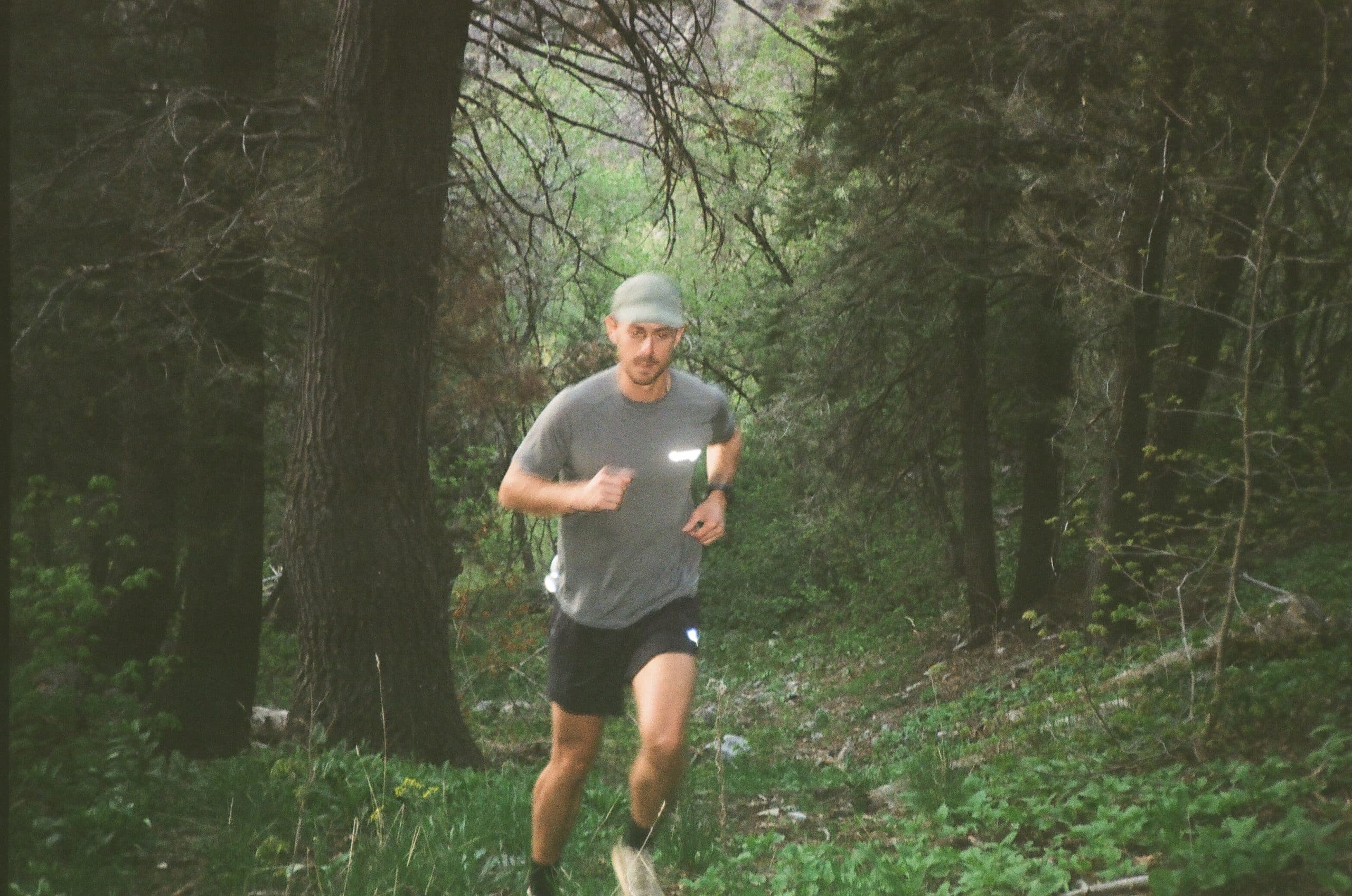 Man running through forest trail in Klättermusen