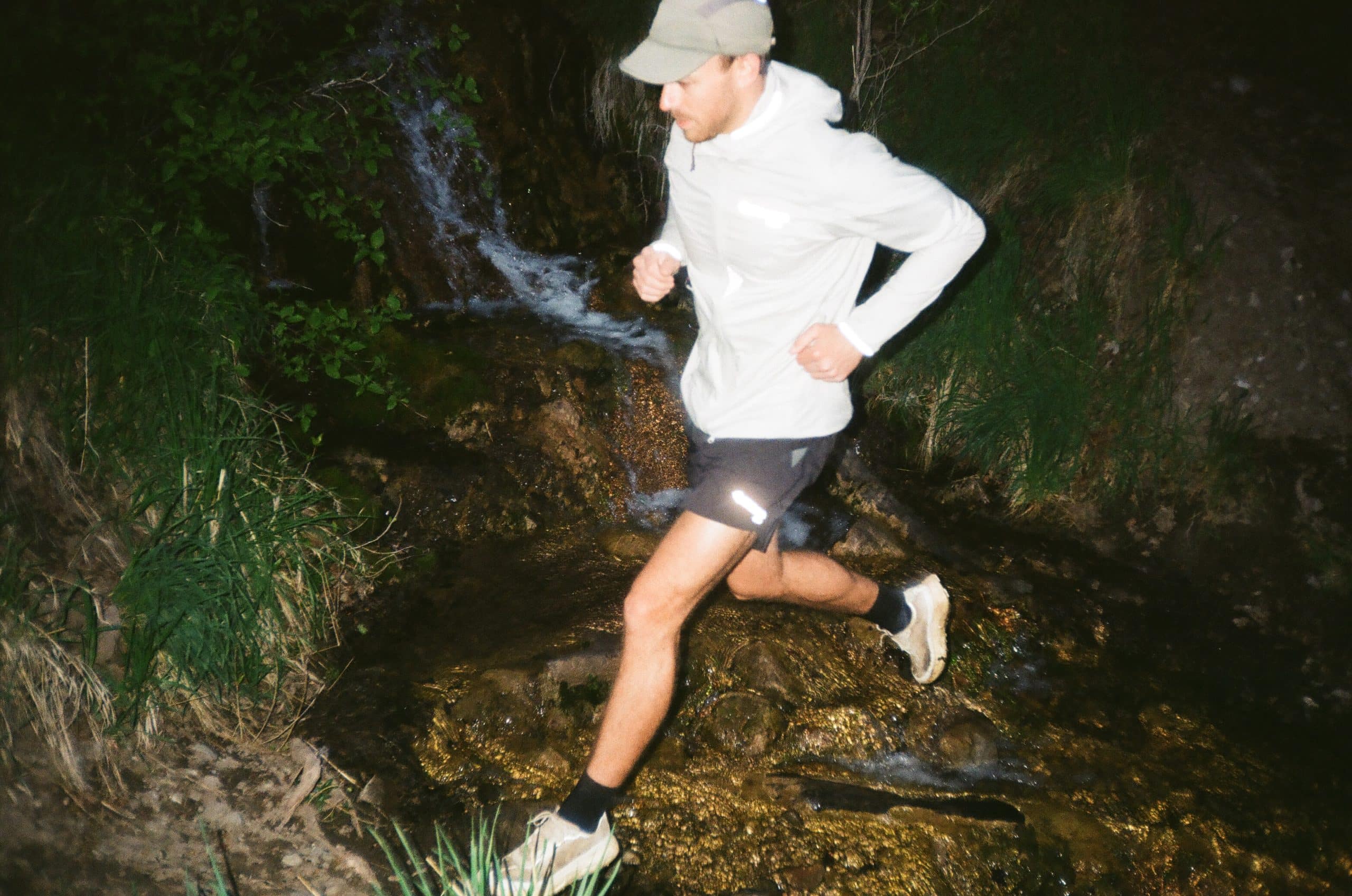 Runner crossing a stream at night.