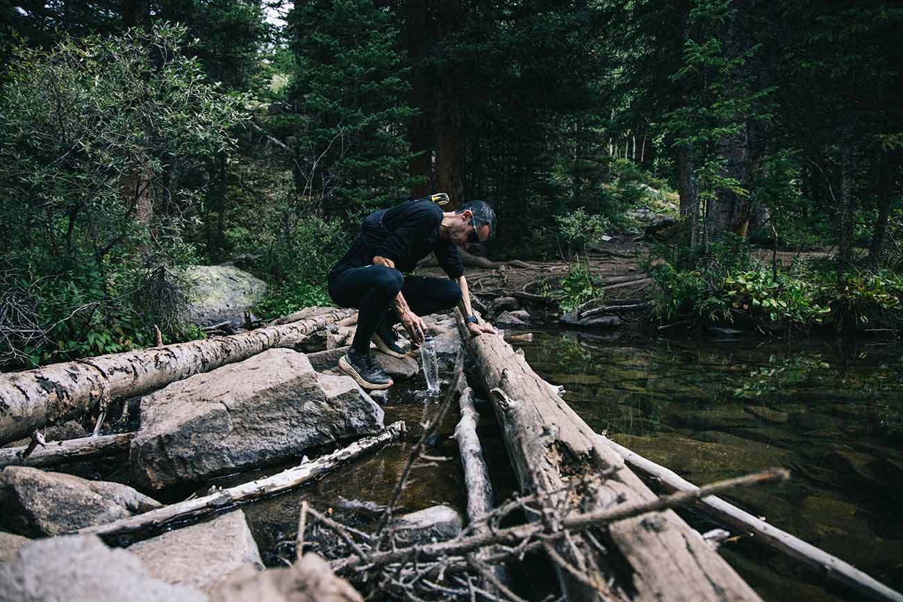 Runner stopping at a river for a drink