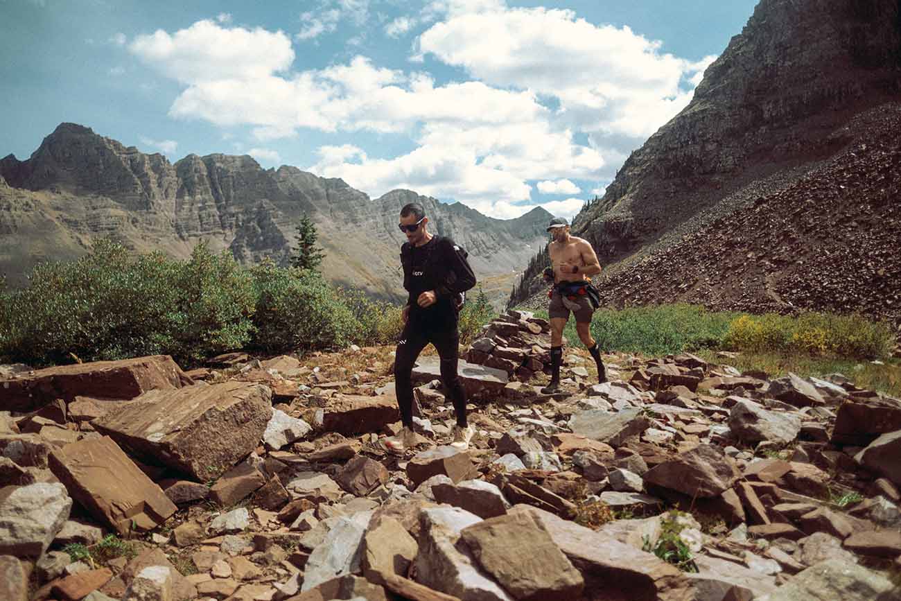 Two people running on rocky terrain in the mountains of Colorado